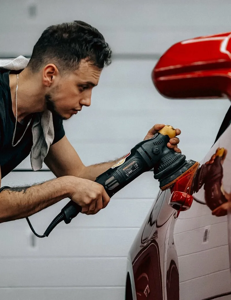 Detailer polishing a car exterior in a garage