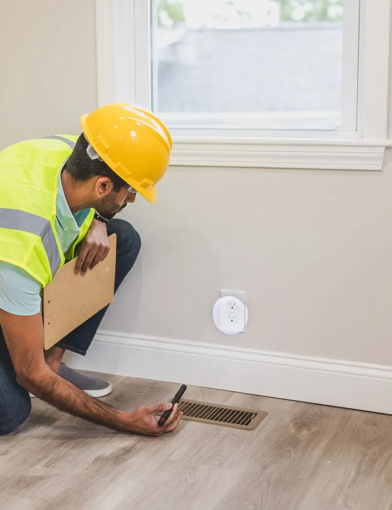 Technician inspecting a floor air vent in a home